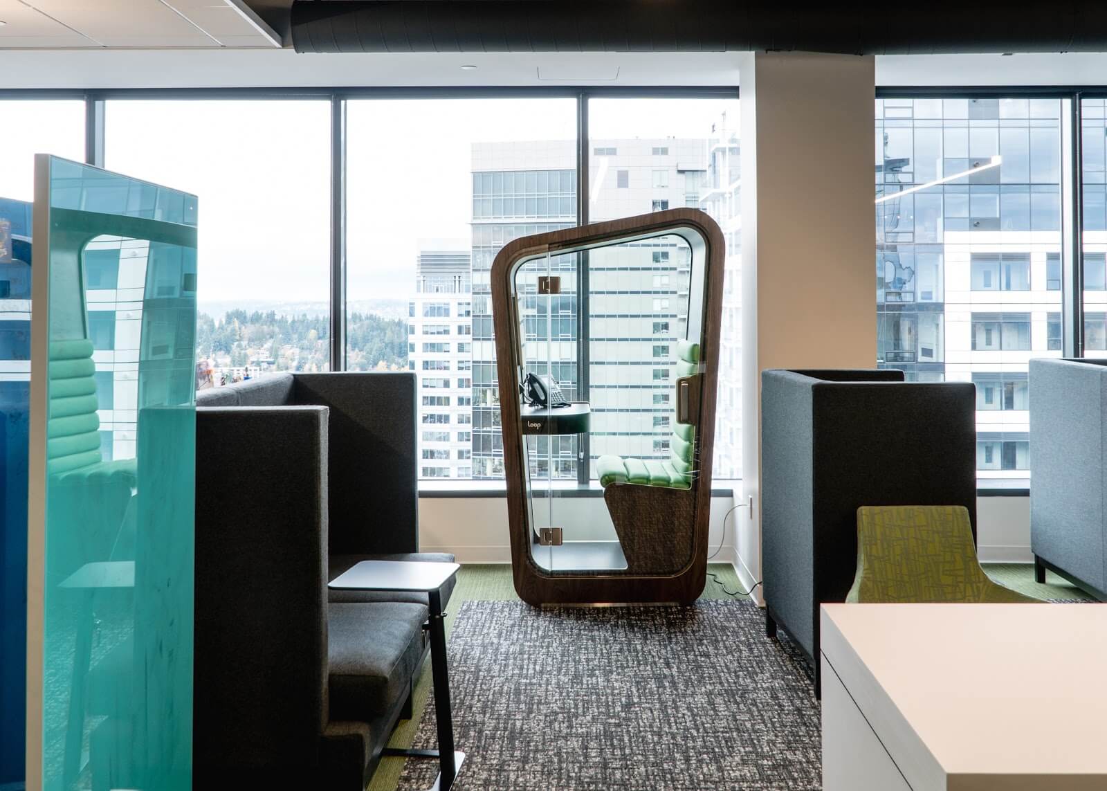 A dark wood Loop Solo with green interior sits in an office space against a large glass window