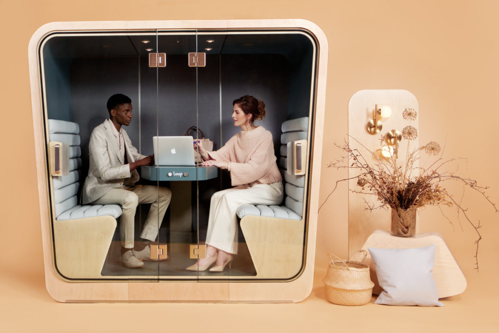 A man and a woman meet in a tan Loop Cube phone booth