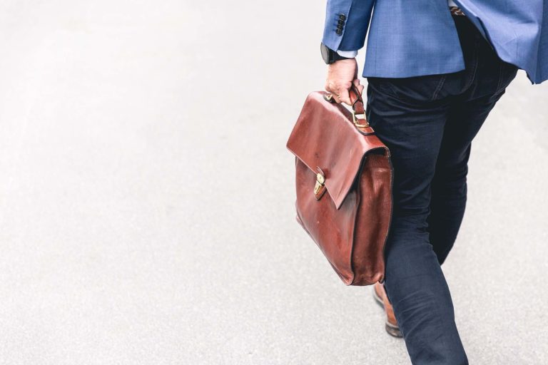 A man in a suit carrying a leather brown briefcase for work