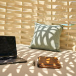 laptop with pillow and journal in an outdoor shaded sitting area