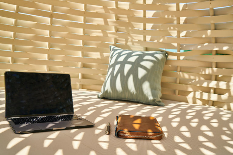 laptop with pillow and journal in an outdoor shaded sitting area