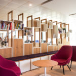 A creative workspace design with magenta office chairs, a modern bookshelf, and open office space