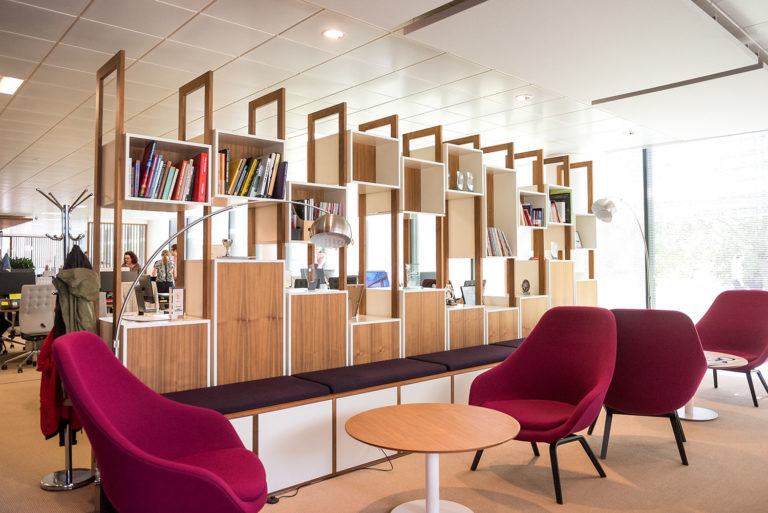A creative workspace design with magenta office chairs, a modern bookshelf, and open office space
