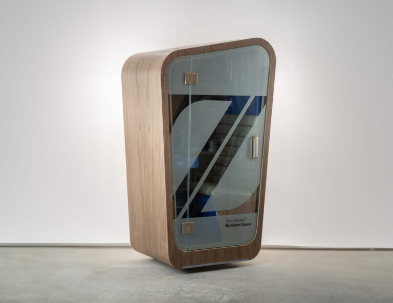 A loop solo phone booth sitting on a concrete floor with custom frosted glass in the shape of a Z and walnut exterior wood