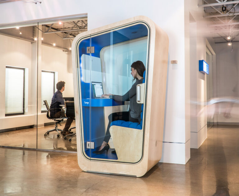Blue interior loop privacy pod with a woman working inside it outside of a conference room inside a modern office