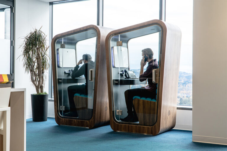 Two Loop Solo Phone Booths with people talking on the phone in them sit in the pokemon offices