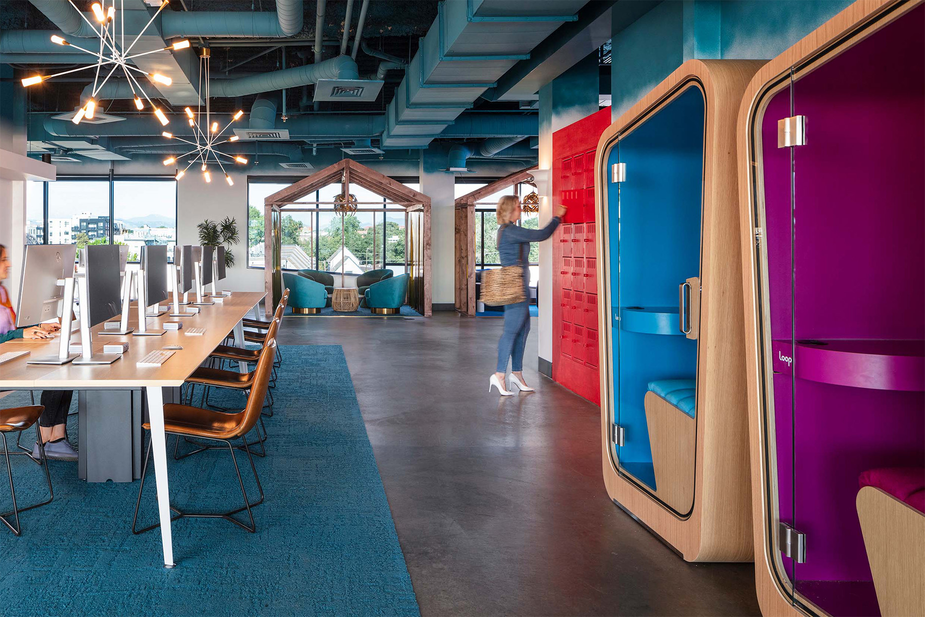 two Loop Solo office pods with vividly colored interiors inside a very colorful open office space